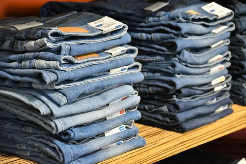 Folded blue jeans stacked on a wooden table