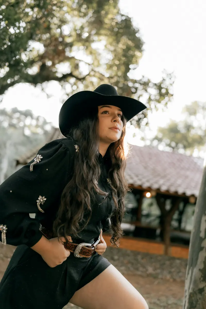 A woman in a black cowboy hat and black western shirt