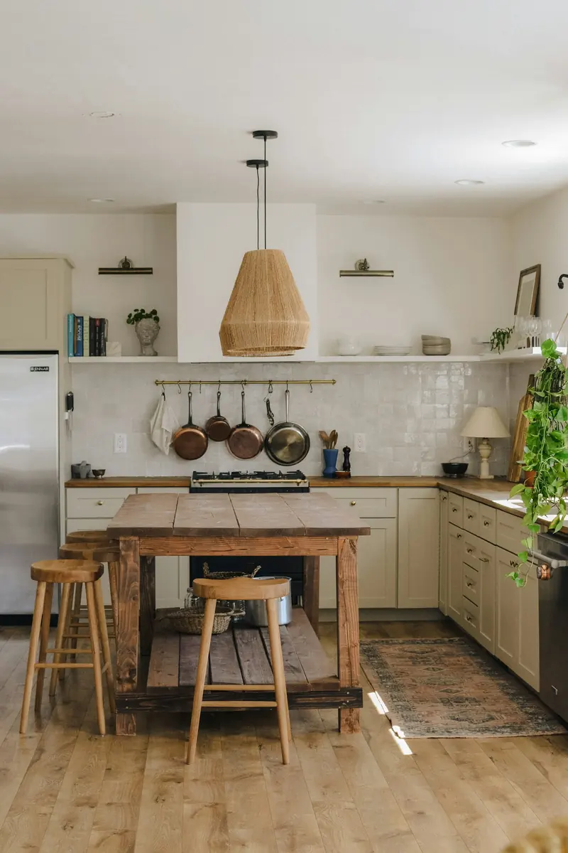 A kitchen with a wood island and woven pendant lights