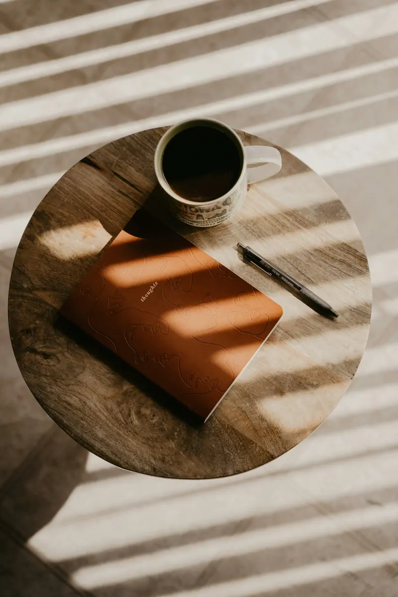 A cup of coffee and a notebook in morning light