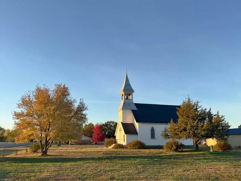 A white country church with a black roof in the evening light