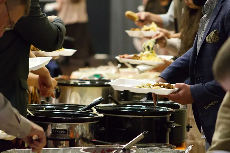 People filling their plates at a potluck line