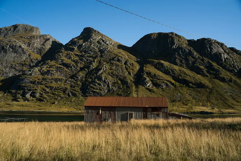 An old barn in a dry field below the mountains