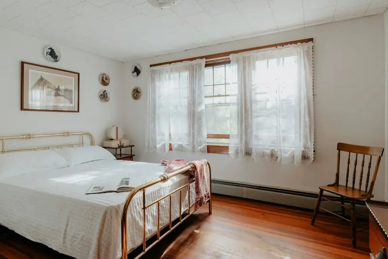 A white bed next to a sunny window