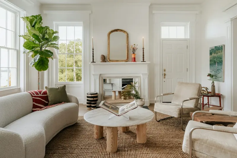 A white living room with a fireplace and a round coffee table