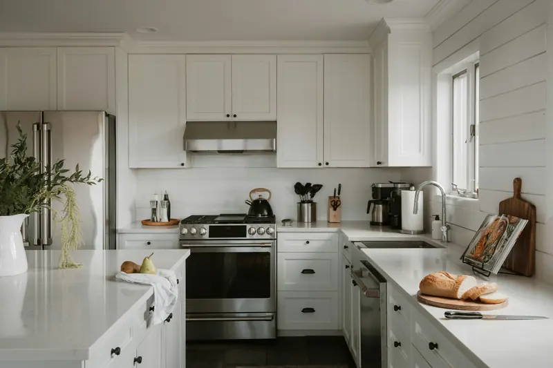 A bright kitchen with white cabinets and fresh bread on the counter