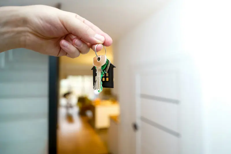 A hand holding house keys in an open doorway