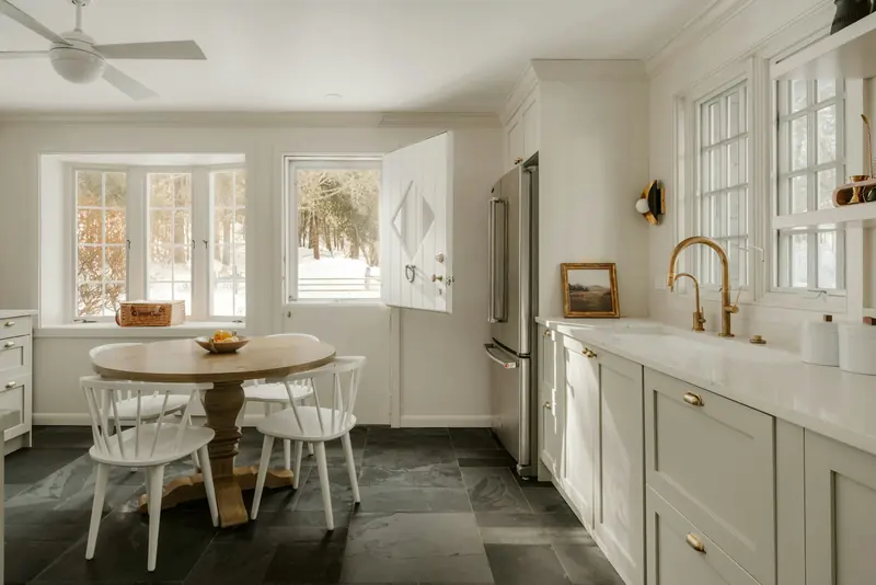 A bright farmhouse kitchen with a round table and a Dutch door