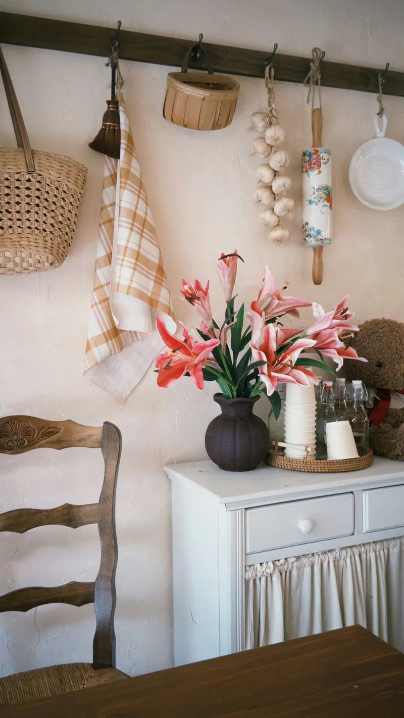 Pink lilies in a vase on a white cabinet with linen towels hanging above