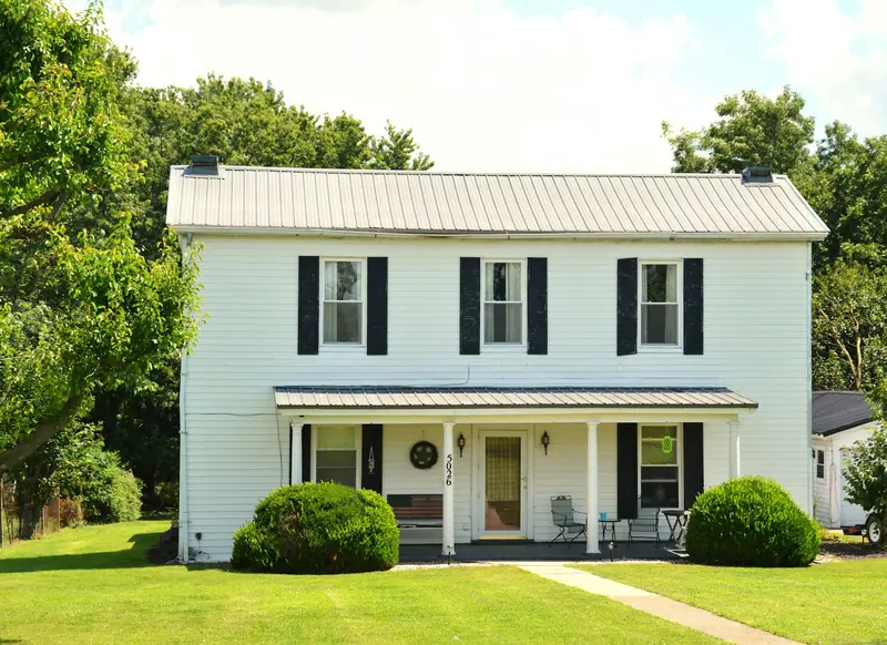 A two-story white house with black shutters and a front porch
