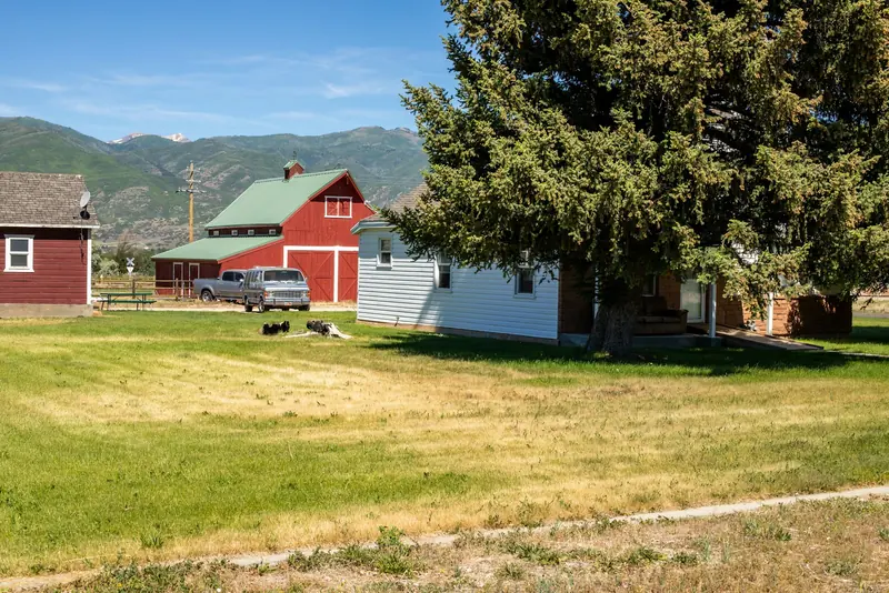 A white house and a red barn under the mountains