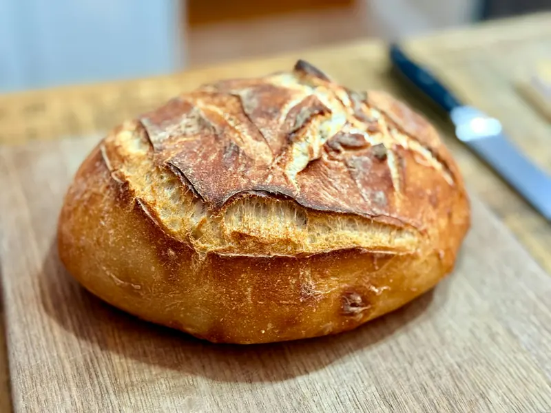 A crusty loaf of bread on a wooden cutting board