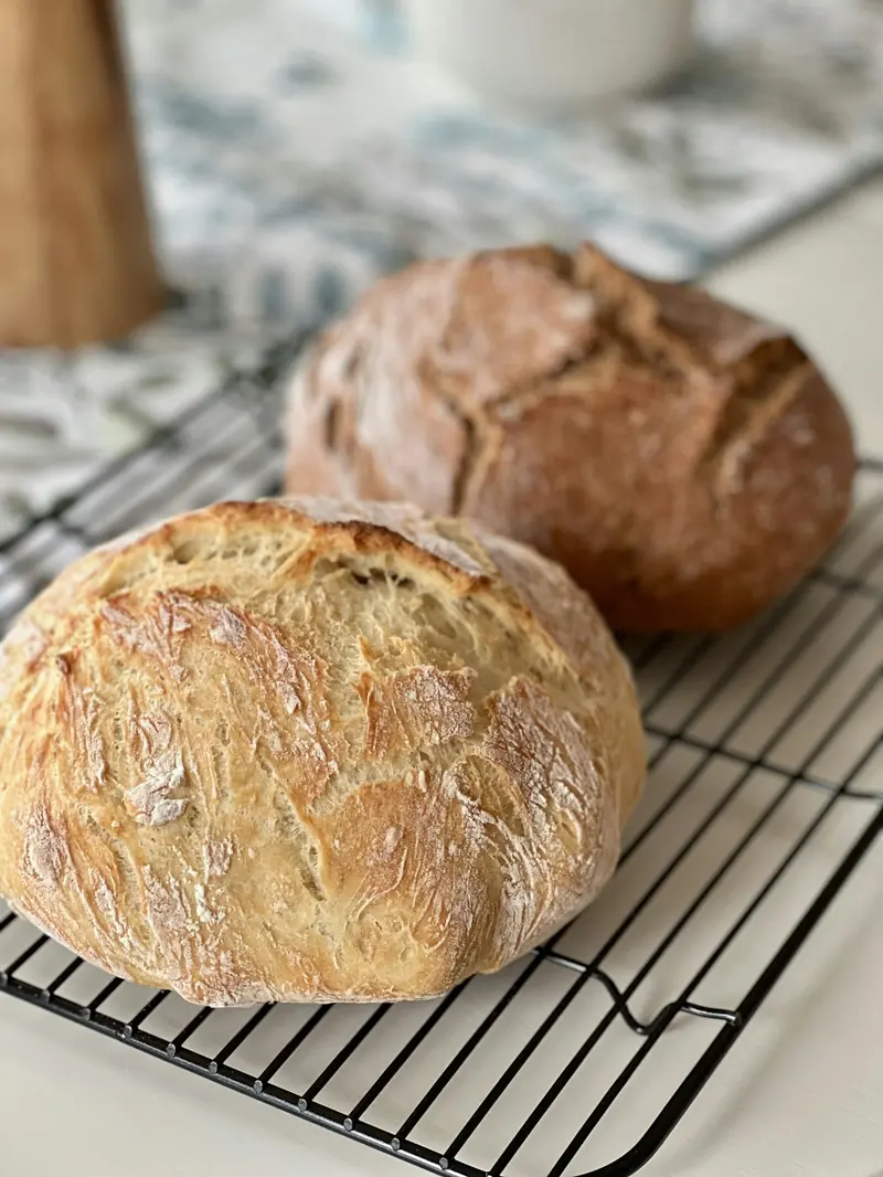 Two crusty loaves cooling on a wire rack