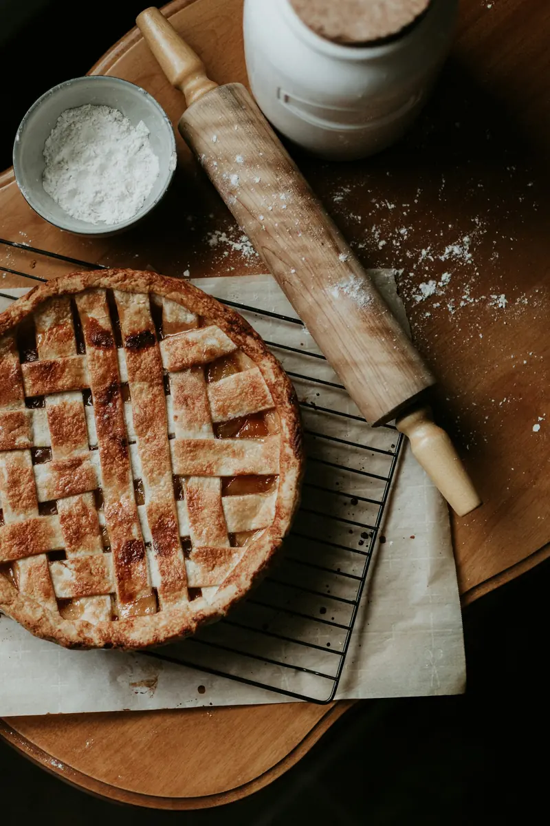 A lattice-top pie cooling beside a rolling pin