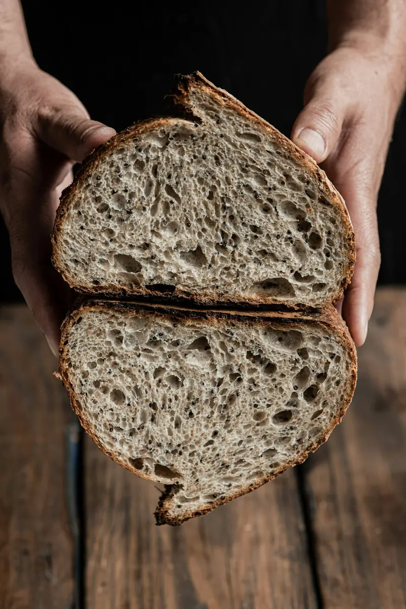 Hands holding a loaf of sourdough torn in half
